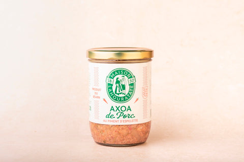 Image d'un plat d'Axoa de Porc traditionnel basque, préparé par Lahouratate, présentant des morceaux de viande de porc tendre dans une sauce onctueuse aux poivrons et aux piments doux, relevée d'une pointe de piment d'Espelette AOP.