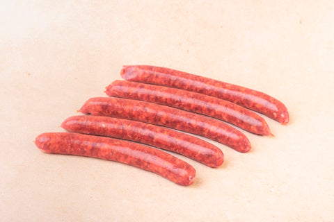 Image de merguez artisanales fraîches conditionnées sous vide, fabriquées à partir de porc béarnais dans les ateliers de la Maison Lahouratate.
